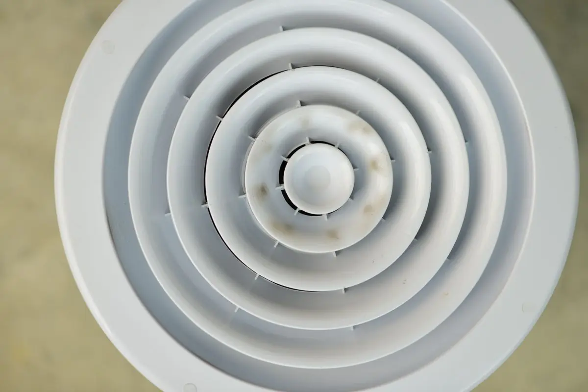 Round ceiling air vent with dust and dirt marks