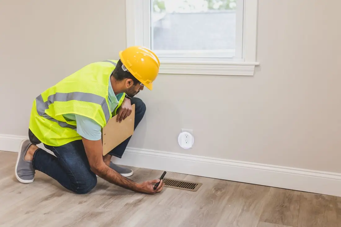 Contractor checking a floor air vent in a home