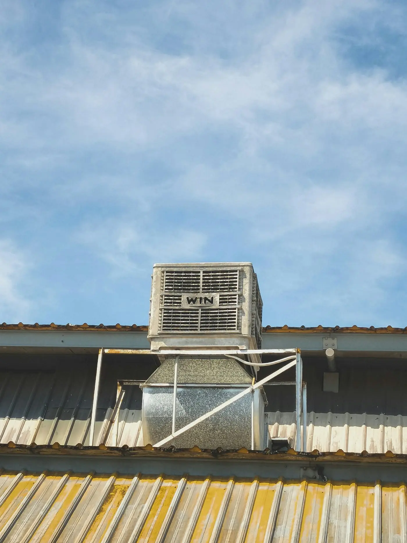 Evaporative swamp cooler mounted on a metal roof